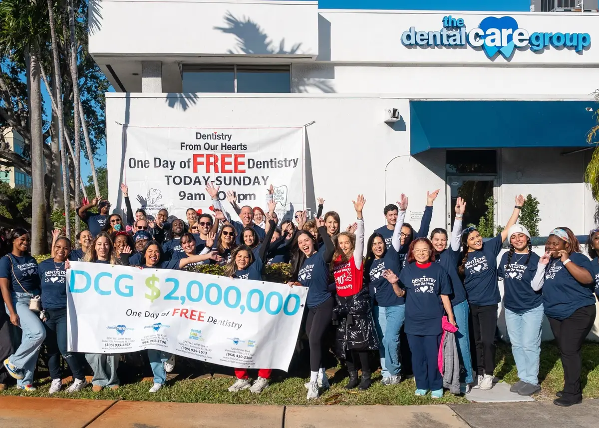 The Dental Care Group team holding a banner for Dentistry From Our Hearts, One Day of Free Dentistry
