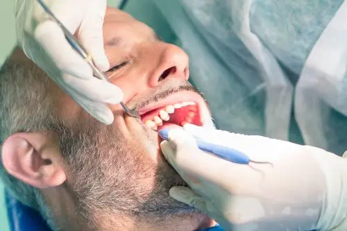 Dentist and assistant performing a deep cleaning (scaling and root planing) on an adult patient